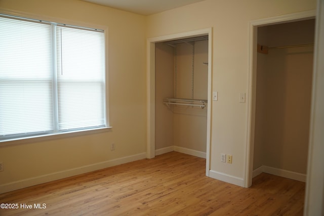 unfurnished bedroom with a closet, baseboards, and light wood-type flooring