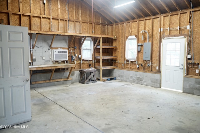 garage with a workshop area, electric panel, and cooling unit