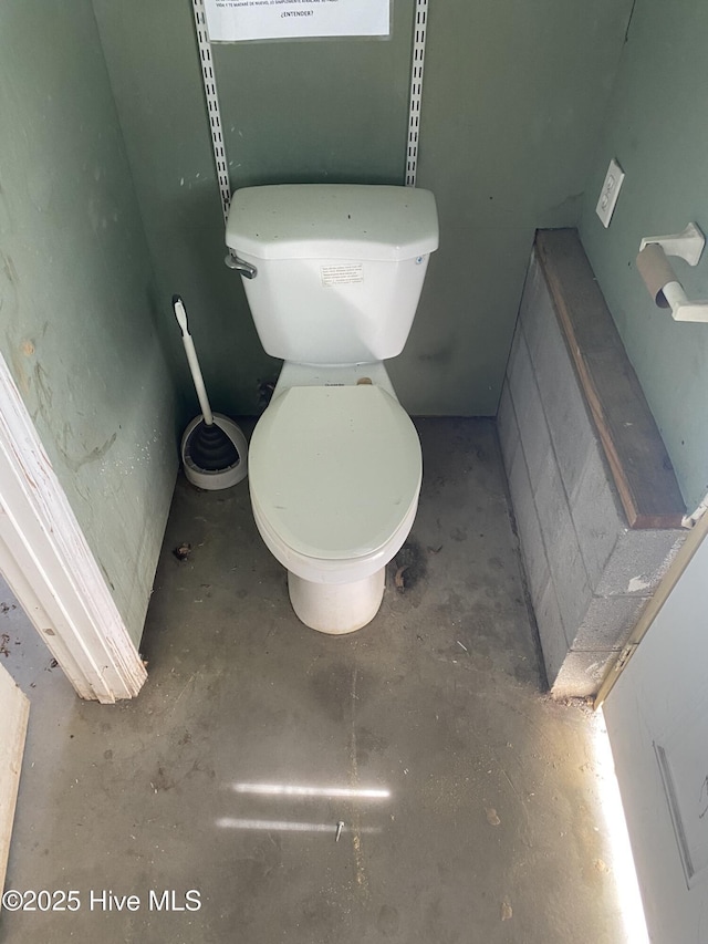 bathroom with toilet and unfinished concrete flooring