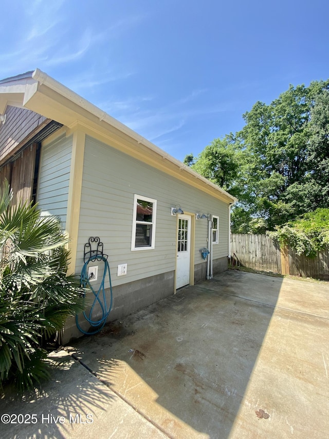 view of property exterior with a patio area and fence