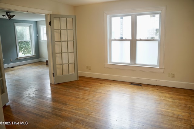 unfurnished room with baseboards, hardwood / wood-style flooring, and visible vents