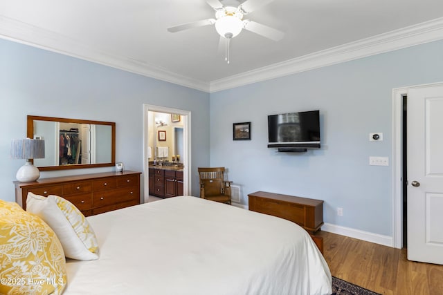 bedroom featuring crown molding, ensuite bath, a ceiling fan, wood finished floors, and baseboards