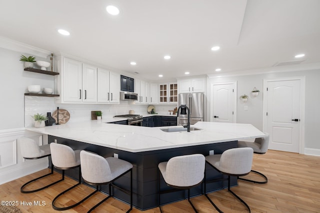 kitchen featuring stainless steel appliances, a peninsula, a sink, open shelves, and ornamental molding
