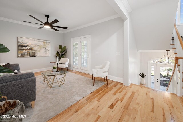 living room with wood finished floors, crown molding, baseboards, and ceiling fan