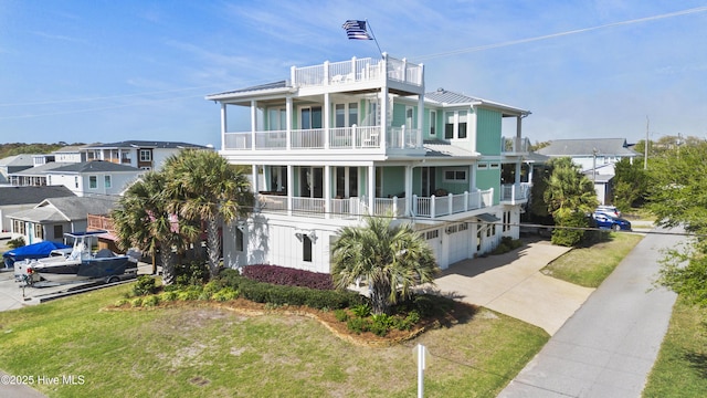 view of front of property featuring a balcony, metal roof, a standing seam roof, driveway, and an attached garage