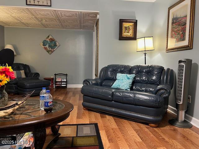 living area with baseboards, wood finished floors, and an ornate ceiling