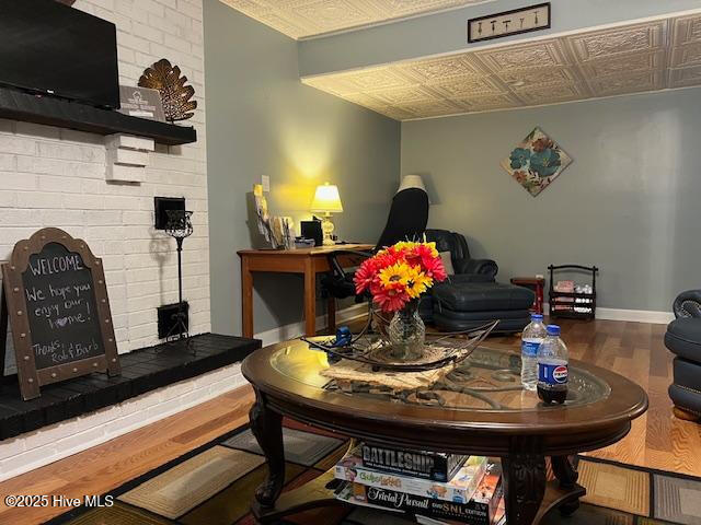 sitting room featuring baseboards, wood finished floors, and an ornate ceiling