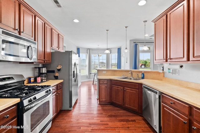 kitchen featuring a peninsula, visible vents, appliances with stainless steel finishes, a sink, and dark wood-style floors