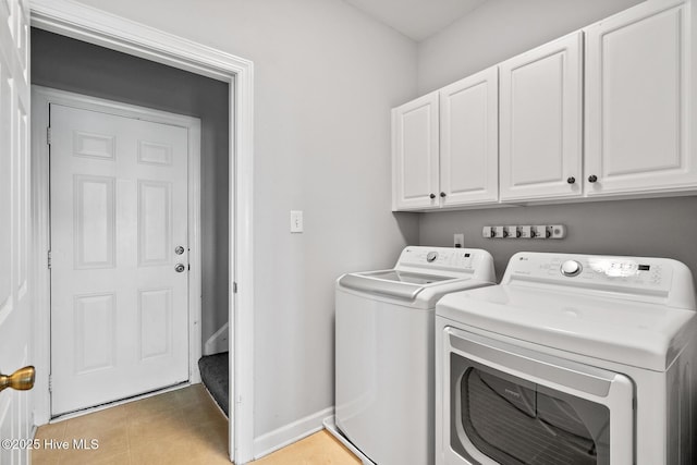 washroom featuring baseboards, cabinet space, and washer and clothes dryer