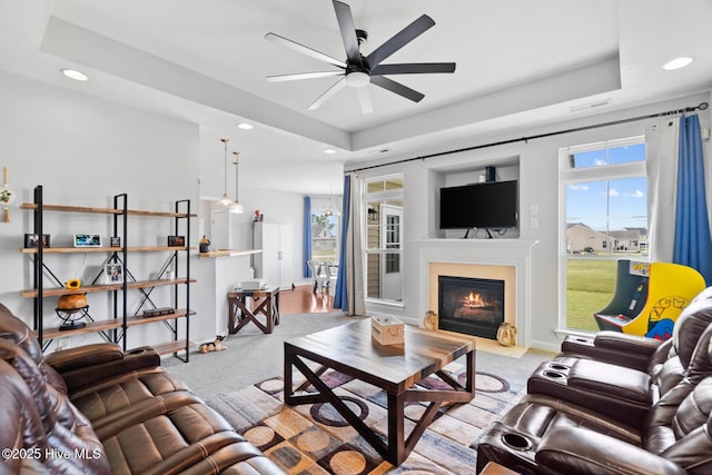 carpeted living room featuring a tray ceiling, ceiling fan, recessed lighting, and a healthy amount of sunlight