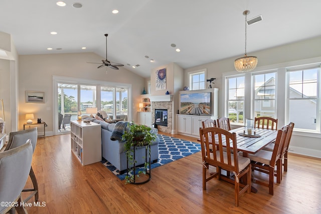 2821 Harborside Way, Southport, NC 28461 - dining room with a glass covered fireplace, light wood finished floors, a ceiling fan, vaulted ceiling, and a chandelier