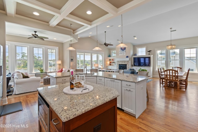2821 Harborside Way, Southport, NC 28461 - kitchen featuring open floor plan, ceiling fan, a kitchen island with sink, beamed ceiling, and coffered ceiling