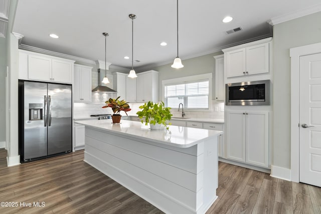 1331 Landover Dr SW, Ocean Isle Beach, NC 28469 - kitchen with appliances with stainless steel finishes, a sink, wall chimney range hood, white cabinetry, and crown molding
