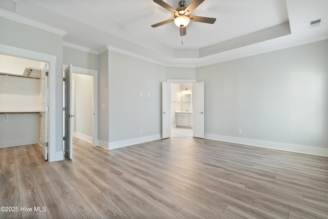 1331 Landover Dr SW, Ocean Isle Beach, NC 28469 - unfurnished bedroom with a tray ceiling, light wood-style flooring, a walk in closet, baseboards, and crown molding