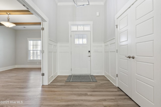 1331 Landover Dr SW, Ocean Isle Beach, NC 28469 - entrance foyer with a decorative wall, crown molding, healthy amount of natural light, light wood-style flooring, and a wainscoted wall