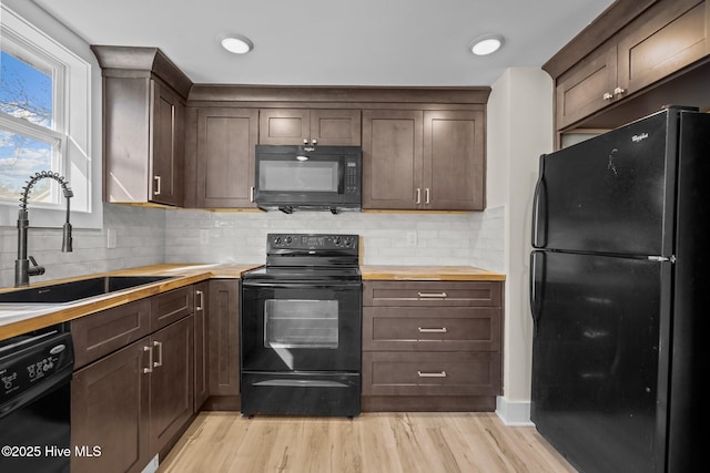 608 S 14th St, Wilmington, NC 28401 - kitchen featuring dark brown cabinetry, butcher block countertops, a sink, light wood-style flooring, and black appliances