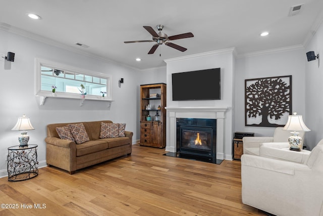 living room featuring ceiling fan, a glass covered fireplace, and light wood-style floors
