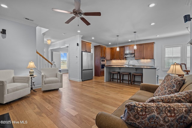 living room with crown molding, ceiling fan, baseboards, visible vents, and recessed lighting
