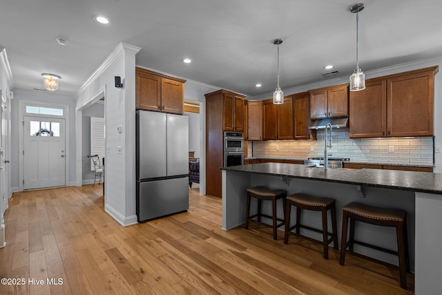kitchen featuring backsplash, crown molding, stainless steel appliances, and a breakfast bar