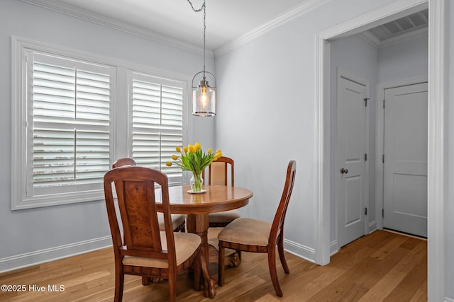 dining space with light wood-type flooring, visible vents, crown molding, and baseboards