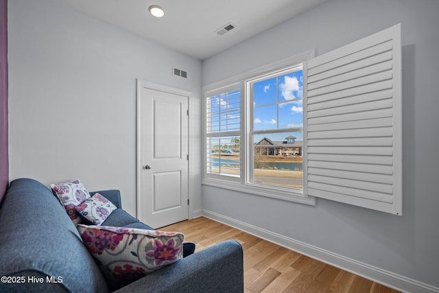 living area featuring baseboards, visible vents, and light wood-type flooring