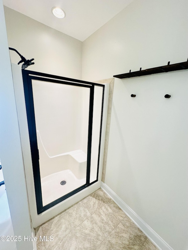 bathroom featuring baseboards, tile patterned floors, and a stall shower