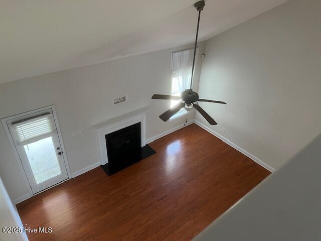 unfurnished living room with baseboards, ceiling fan, and dark wood-type flooring