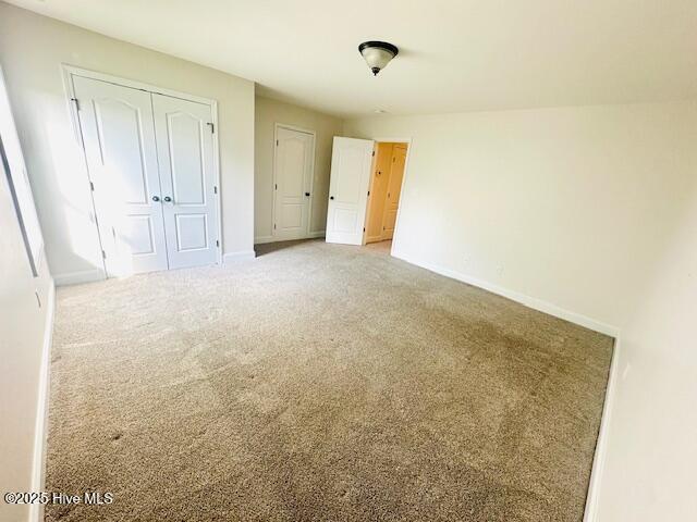 unfurnished bedroom with carpet floors, baseboards, and a closet