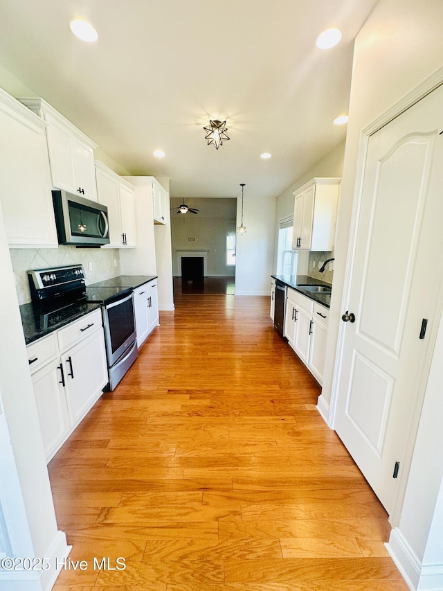 kitchen featuring dark countertops, ceiling fan, white cabinetry, a sink, and appliances with stainless steel finishes