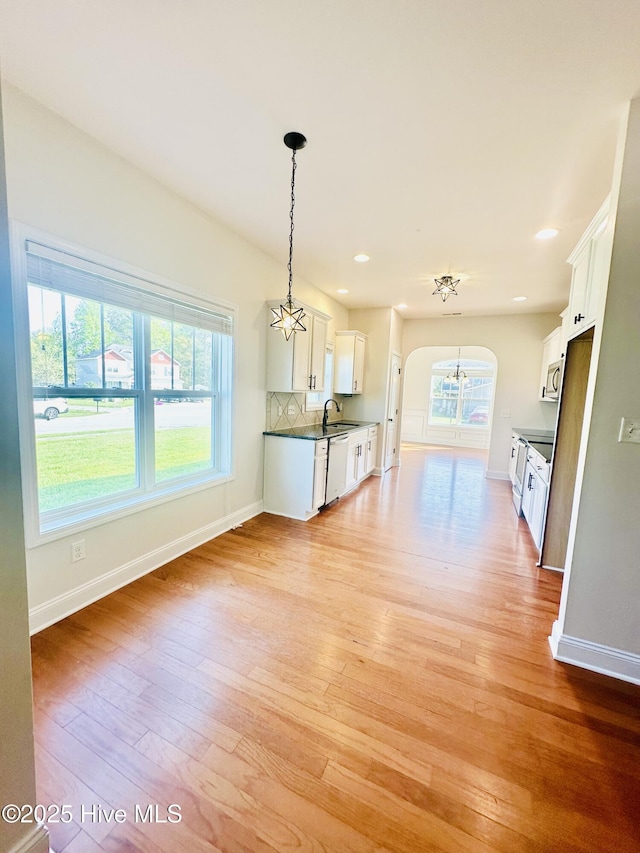 interior space featuring a notable chandelier, a sink, light wood finished floors, arched walkways, and baseboards