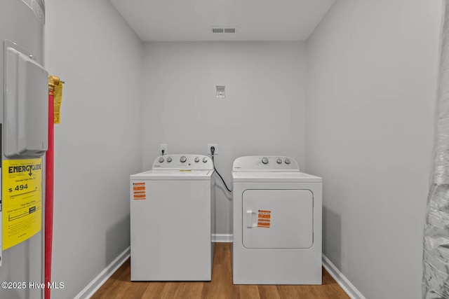 washroom featuring visible vents, baseboards, laundry area, wood finished floors, and washing machine and clothes dryer