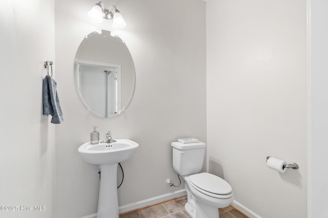 bathroom featuring toilet, tile patterned floors, a sink, and baseboards