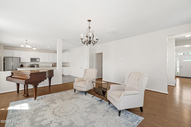 living area featuring a chandelier, wood finished floors, and baseboards