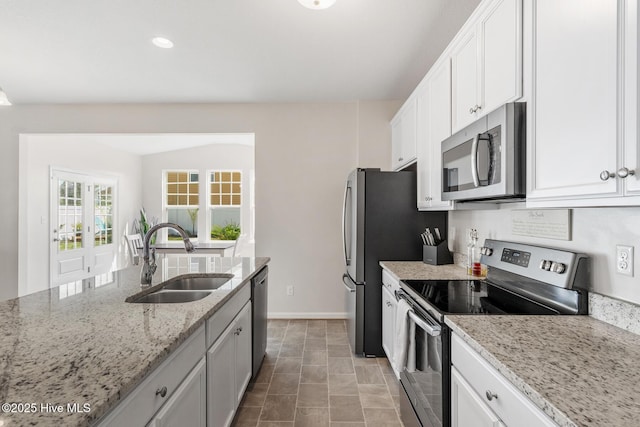 kitchen with white cabinets, baseboards, a sink, appliances with stainless steel finishes, and light stone countertops
