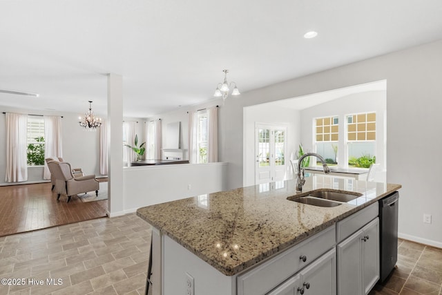 kitchen with a kitchen island with sink, a sink, a notable chandelier, and dishwasher
