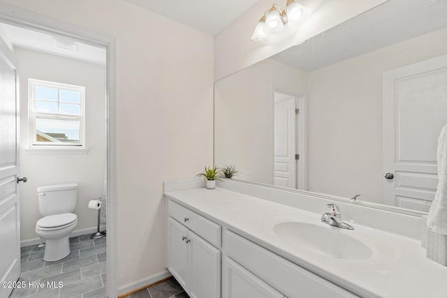 bathroom with toilet, vanity, and baseboards