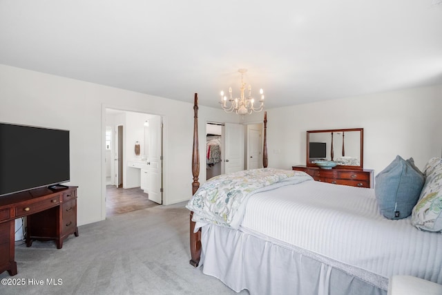 bedroom with a closet, a spacious closet, a chandelier, ensuite bath, and light colored carpet