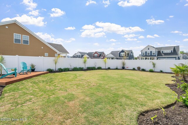view of yard with a fenced backyard, a deck, and a residential view