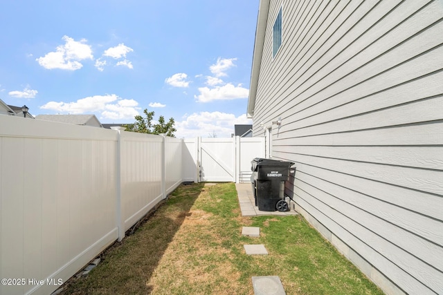 view of yard with a fenced backyard and a gate