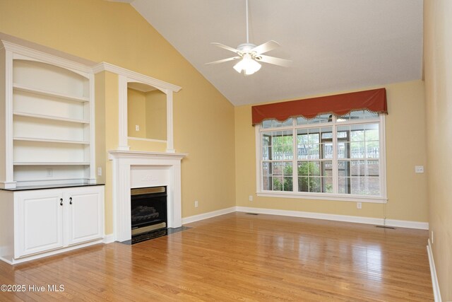 995 Monticello Dr, Pinehurst, NC 28374 - unfurnished living room with light wood-style floors, ceiling fan, vaulted ceiling, a fireplace with flush hearth, and baseboards