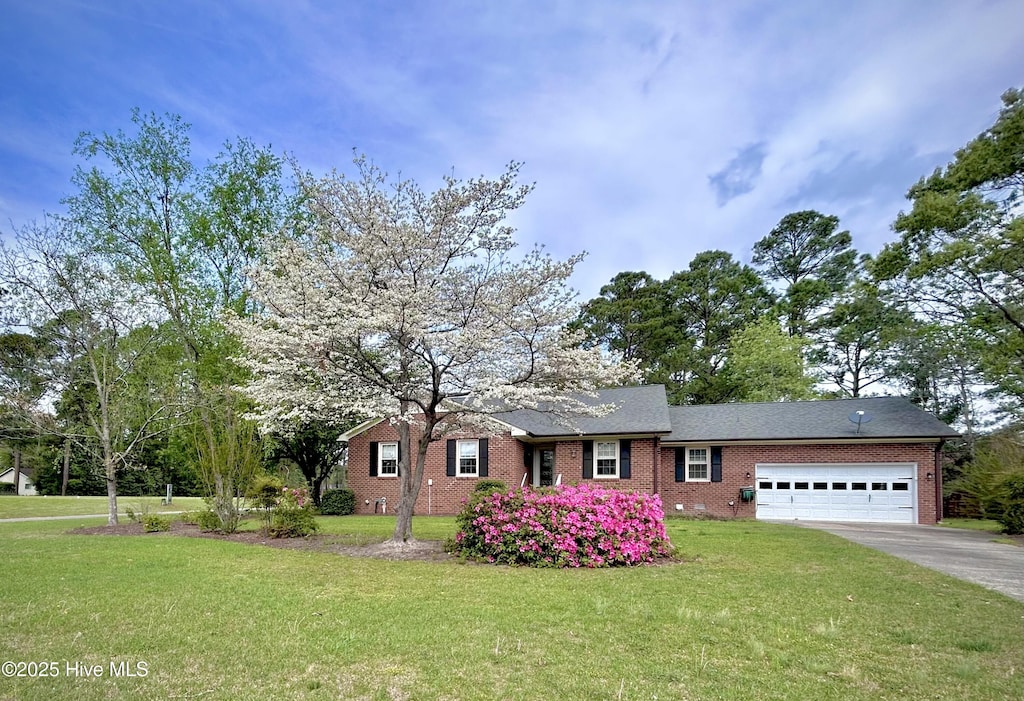 single story home featuring a front lawn, driveway, brick siding, and a garage