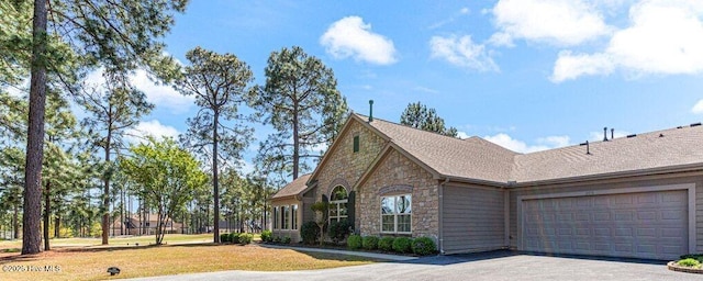105 W Chelsea Ct, Southern Pines, NC 28387 - view of front of house with an attached garage, stone siding, driveway, and a front lawn