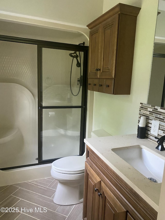 bathroom featuring vanity, toilet, backsplash, and a stall shower