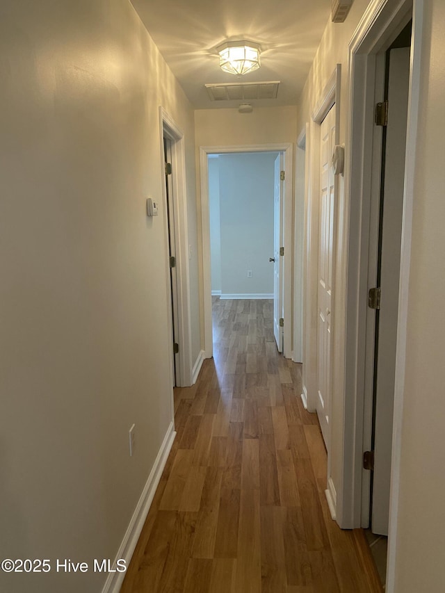 corridor featuring baseboards and wood finished floors