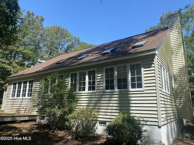 view of home's exterior with a chimney and a wooden deck