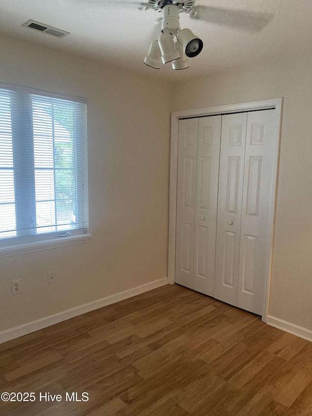unfurnished bedroom featuring baseboards, a closet, light wood-type flooring, and visible vents