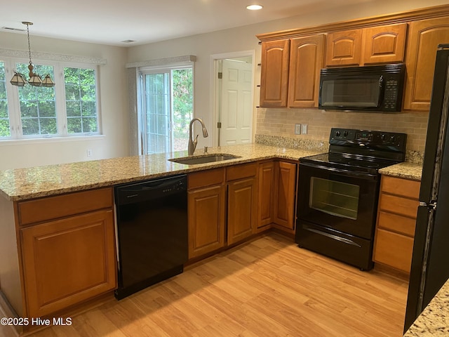 kitchen featuring brown cabinets, a sink, black appliances, and light wood-type flooring