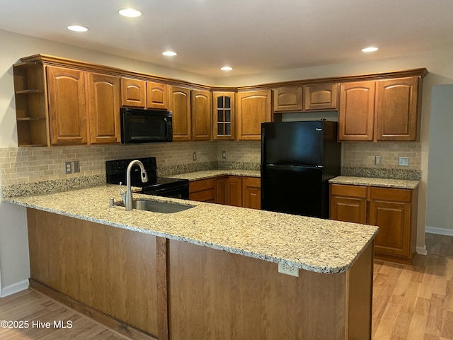 kitchen with light wood-type flooring, a sink, a peninsula, and black appliances