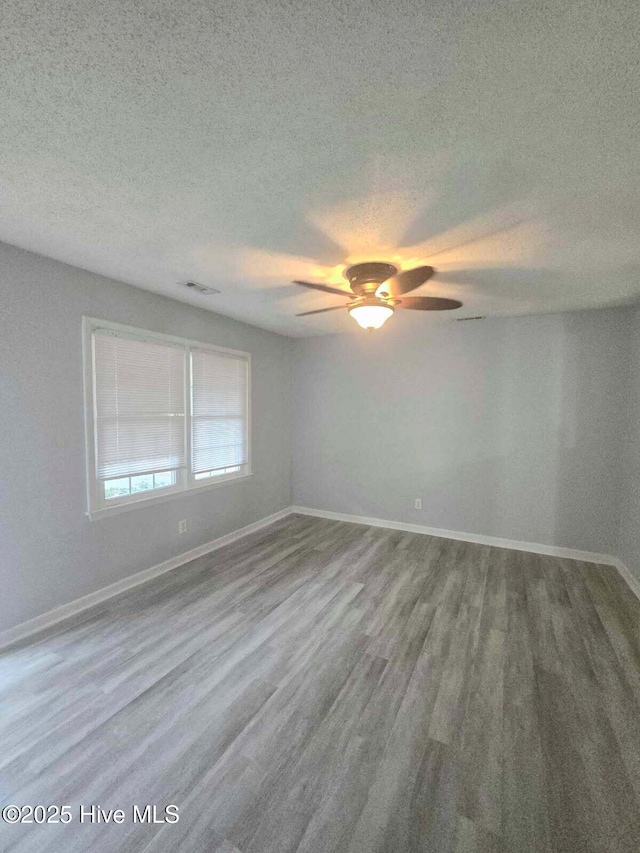 spare room featuring baseboards, wood finished floors, and ceiling fan