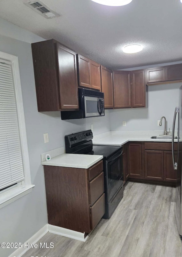 100 Knight Pl, Jacksonville, NC 28546 - kitchen featuring black appliances, light wood-type flooring, light countertops, a sink, and a textured ceiling